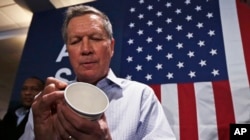 Ohio Gov. John Kasich, a candidate for the Republican presidential nomination, autographs a paper cup for a guest during a campaign stop in Atkinson, N.H., Feb. 5, 2016.