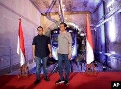 Presiden Indonesia Joko Widodo berdiri di atas panggung dengan Gubernur Jakarta Anies Baswedan di Jakarta, Indonesia. (Foto: AP)