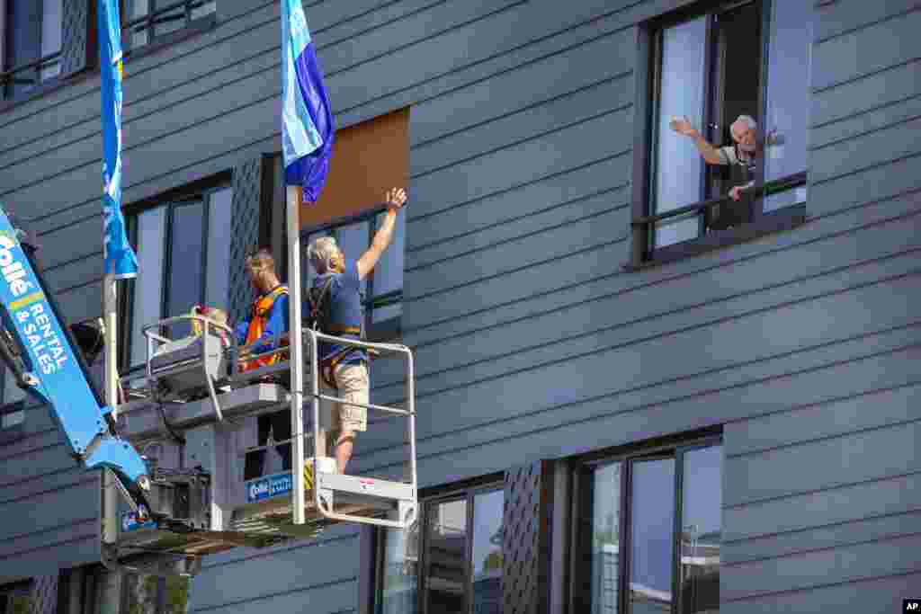 Pitrik van der Lubbe waves from a crane to his 88-year-old father Henk, right, at a nursing home in Gouda, Netherlands. The crane was made available for free by a company to permits family members to see their loved ones in isolation because of the coronavirus.