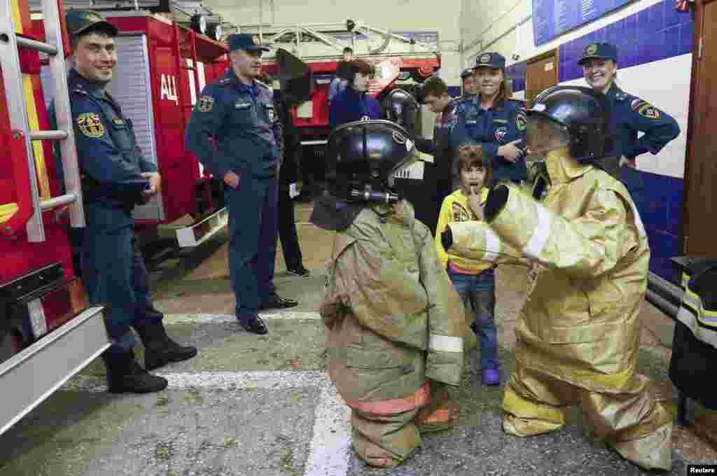 Children who fled the fighting in the eastern regions of Ukraine, wear firefighter suits during an excursion to a fire station in Krasnoyarsk, Russia.