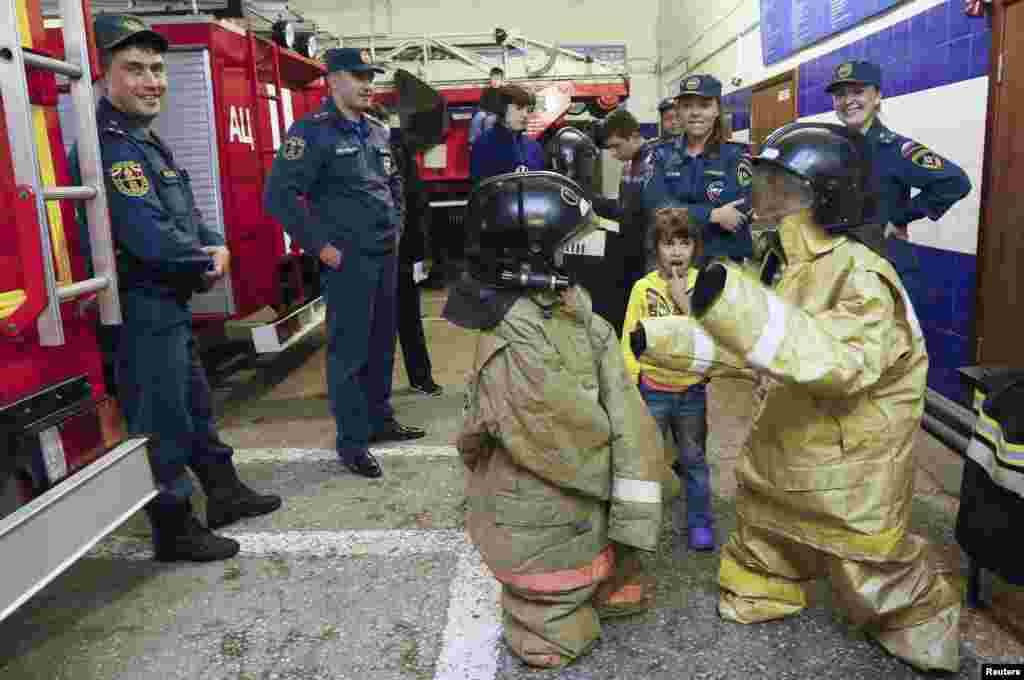 Children who fled the fighting in the eastern regions of Ukraine, wear firefighter suits during an excursion to a fire station in Krasnoyarsk, Russia. 