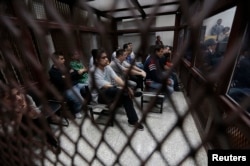 FILE - Members of a gang sit behind bars at a court that deals with gender-based crimes in Guatemala City, July 3, 2013.