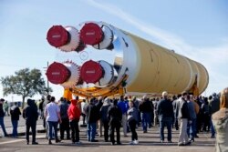 FILE - Employees and contractors watch as the core stage of NASA's Space Launch System rocket, that will be used for the Artemis 1 Mission, is moved to the Pegasus barge, at the NASA Michoud Assembly Facility where it was built, in New Orleans, Jan. 8, 2020.