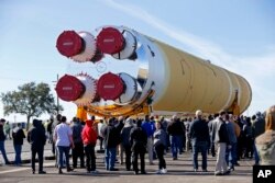 FILE - Employees and contractors watch as the core stage of NASA's Space Launch System rocket, that will be used for the Artemis 1 Mission, is moved to the Pegasus barge, at the NASA Michoud Assembly Facility where it was built, in New Orleans, Jan. 8, 2020.