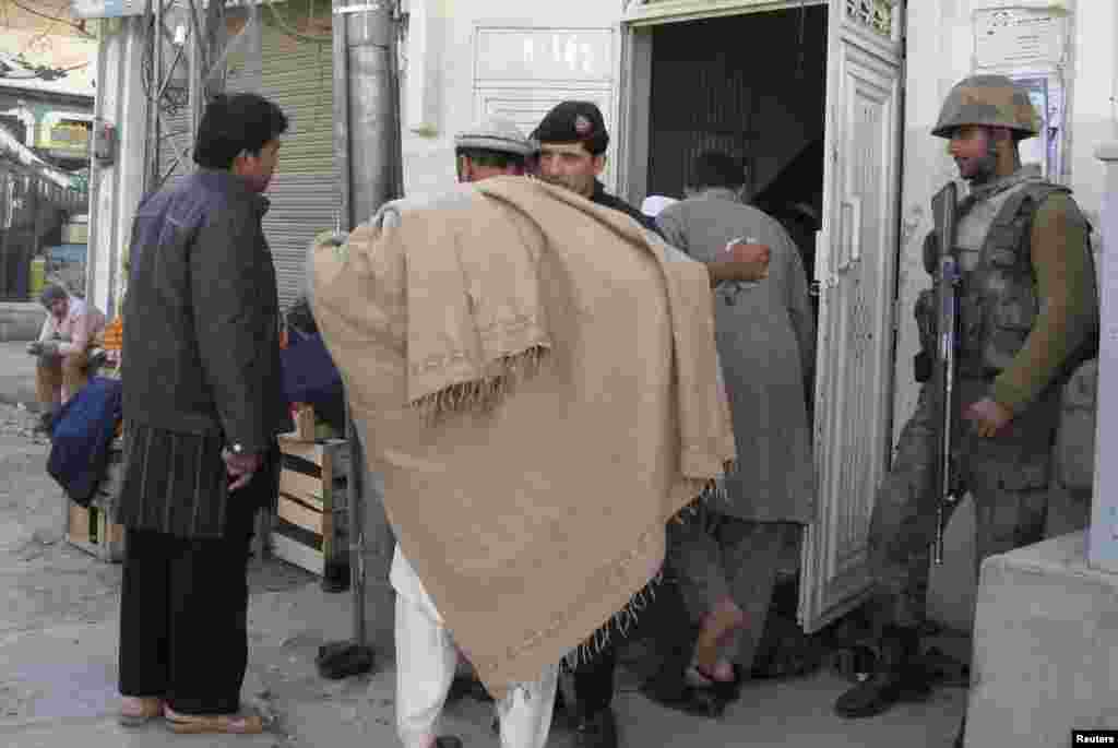 A paramilitary soldier frisks a man at the entrance of a mosque in Mingora, Swat valley, Pakistan a day after deadly bombings, January 11, 2013.