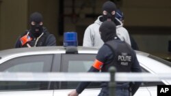 Cảnh sát Bỉ bước vào một chiếc ôtô đỗ bên ngoài một tòa án nơi Salah Abdeslam, nghi can chính trong vụ đánh bom ở Paris năm ngoái, dự kiến trình diện trước một thẩm phán ở Brussels hôm 24/3. 