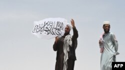 Một người đứng ở biên giới trên phần đất Afghanistan, cầm cờ Taliban.