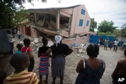 Locals watch a collapsed school damaged by an earthquake of magnitude 5.9 the previous night, in Gros Morne, Haiti, on October 7, 2018.