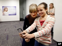 Taylor Swift poses for a photo with Piper Moralez, 11, at the Country Music Hall of Fame and Museum, Oct. 12, 2013, in Nashville, Tenn. Swift is at the facility to open the $4 million Taylor Swift Education Center.
