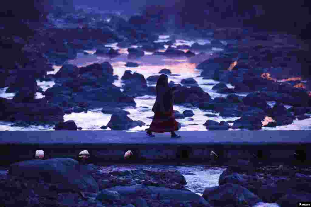 A devotee crosses the Triveni River in the early morning as she arrives to offer prayer during the Swasthani Bratakatha festival in Panauti near Kathmandu, Nepal, Jan. 24, 2015.