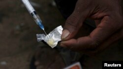 A syringe sucks up a mixture of heroin and water prepared on a foil wrap as addicts shoot up in Stone Town, Zanzibar, Dec. 2009 file photo.