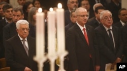 Palestinian President Mahmoud Abbas, left, attends a Christmas Midnight Mass at the Church of the Nativity in the West Bank town of Bethlehem, early Friday, Dec. 25, 2015.