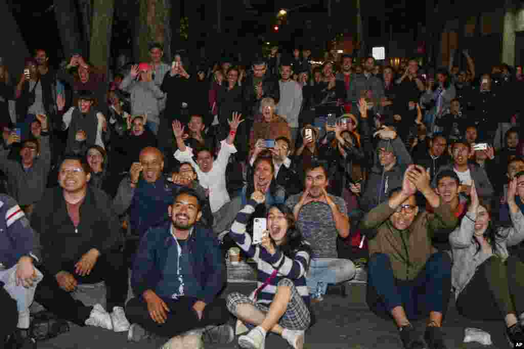 People react as they watch the film &quot;Roma,&quot; by Mexican Director Alfonso Cuaron, win the Oscar for best foreign language film at the 91st Academy Awards, shown on a screen installed for a watch party in a plaza in the Roma neighborhood of Mexico City, Feb. 24, 2019.
