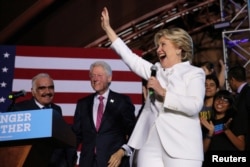 U.S. Democratic presidential candidate Hillary Clinton waves as she arrives to speak at a campaign event after the third and final 2016 presidential campaign debate, accompanied by former President Bill Clinton and Mexican singer Vicente Fernandez (L), in Las Vegas, Oct. 19, 2016.