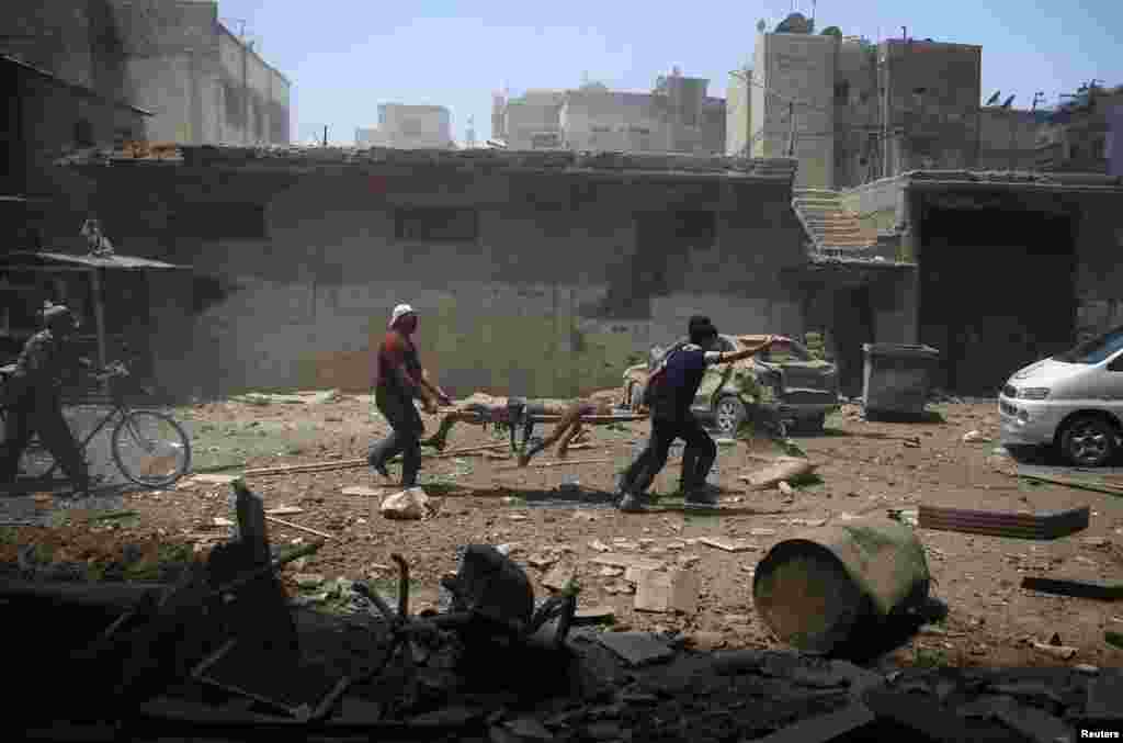 Men transport a casualty at a site hit by airstrikes in the rebel held Douma neighborhood of Damascus, Syria, July 25, 2016.