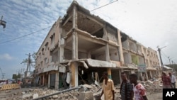 FILE - Men walk near destroyed buildings as thousands of Somalis gathered to pray at the site of the country's deadliest bomb attack, Oct. 20, 2017. Officials now say 512 people were killed in the Oct. 14 attack.