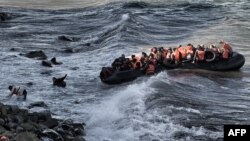 Refugees and migrants try to reach the shore on the Greek island of Lesbos, despite a rough sea, after crossing the Aegean Sea from Turkey, Oct. 30, 2015..