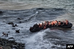 FILE - Refugees and migrants try to reach the shore on the Greek island of Lesbos, despite a rough sea, after crossing the Aegean Sea from Turkey, Oct. 30, 2015.