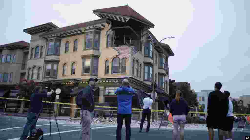 People look at a damaged building with a top corner exposed following an earthquake in Napa, California, Aug. 24, 2014.
