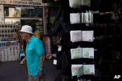 An elderly man walks past wallets designed as euro banknotes, outside a kiosk in central Athens, June 16, 2017. After months of haggling that raised fears of another escalation in Greece's debt crisis, the 19-country eurozone agreed late Thursday to clear the release of a further 8.5 billion euros ($9.5 billion) after the Greek government delivered on an array of reforms.