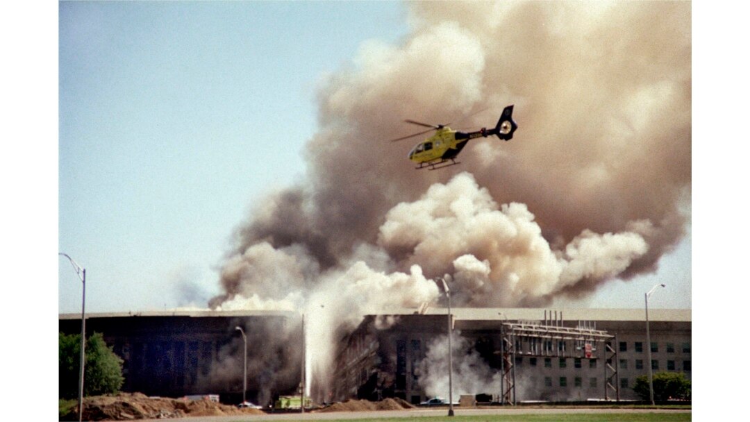 Sebuah helikopter terbang di atas Pentagon, Washington D.C., saat asap mengepul di atas gedung pada 11 September 2001, setelah sebuah pesawat yang dibajak menabrak sisi barat gedung, menewaskan 184 orang. (AP)