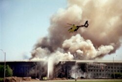 Sebuah helikopter terbang di atas Pentagon, Washington D.C., saat asap mengepul di atas gedung pada 11 September 2001, setelah sebuah pesawat yang dibajak menabrak sisi barat gedung, menewaskan 184 orang. (AP)