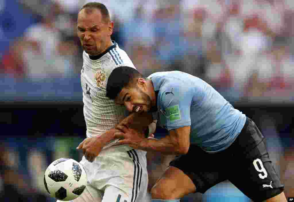 Uruguay&#39;s Luis Suarez, right, and Russia&#39;s Sergei Ignashevich fight for the ball during the group A match between Uruguay and Russia at the 2018 soccer World Cup at the Samara Arena in Samara, Russia.