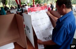 Seorang pria memperhatikan contoh surat suara dalam simulasi pemilu yang diselenggarakan Komisi Pemilihan Umum di Jakarta, Indonesia, 10 April 2019.