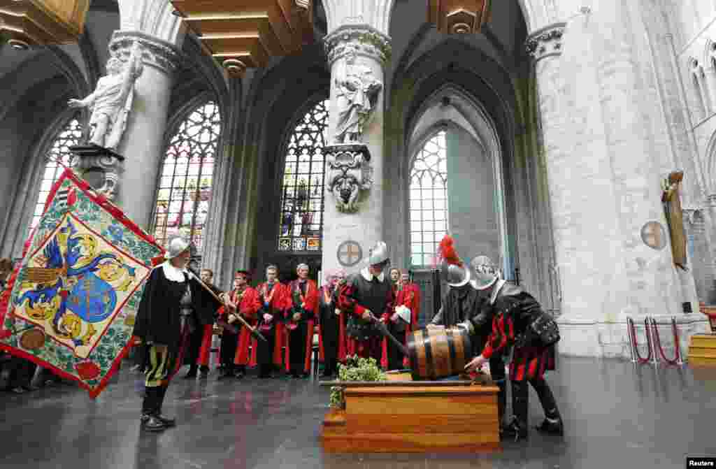 Members of the Knighthood of the Brewers&#39; Mash staff carry a barrel of beer inside the Sint-Gudule Cathedral in Brussels, Belgium, during celebrations of Saint-Arnould, patron saint of brewers.