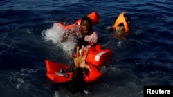 Migran mencoba untuk tetap mengapung setelah jatuh dari perahu karet mereka selama operasi penyelamatan oleh kapal LSM Migrant Offshore Aid Station (MOAS) yang berbasis di Malta di Mediterania tengah di perairan internasional. (Foto: Reuters)