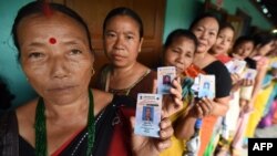 Indian voters pose for a photograph with their identity cards as they queue to cast their ballots in the state assembly elections at a polling station in Diphu in the Karbi Anglong district some 215 kms from Guwahati on April 4, 2016. 
