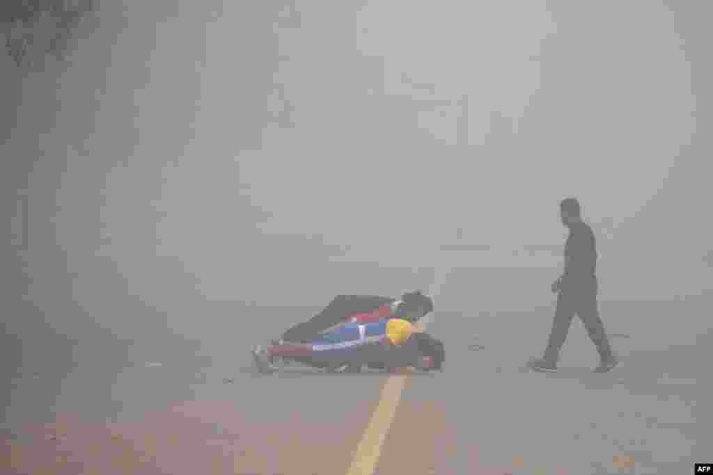 Warga India melakukan olahraga pada hari yang tertutup kabut tebal akibat polusu di India Gate, New Delhi.