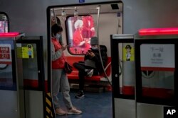 Commuters wearing face masks to help curb the spread of the coronavirus browse their smartphones inside a subway train in Beijing Wednesday, Feb. 10, 2021.