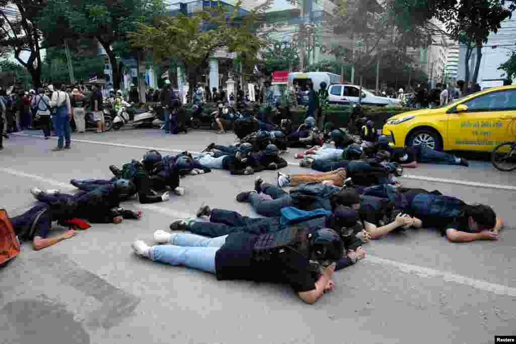 Demonstrators take cover from rubber bullets during a clash with the police while protesting against the amendment of the lese majeste law, in Bangkok, Thailand.
