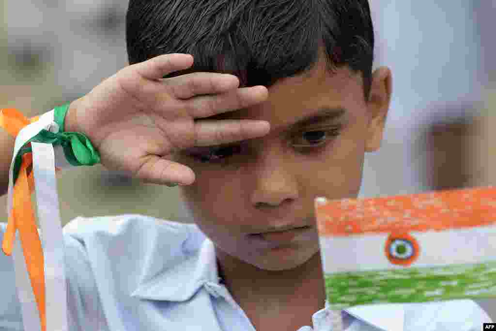 An Indian school student salutes as he holds his hand-made national flag during celebrations of the 68th Independence Day at his school in Kolkata.