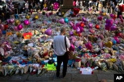 FILE - A man stands next to flowers for the victims of Monday's bombing at St Ann's Square in central Manchester, England, May 26 2017.