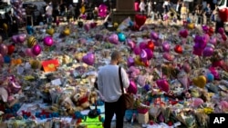 FILE - A man stands next to flowers for the victims of the arena bombing at St. Ann's Square in central Manchester, England, May 26, 2017.