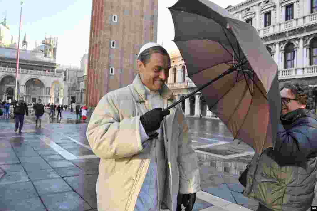 Actor Jude Law holds up an umbrella to block a photographer on the set of Italian director Paolo Sorrentino&#39;s TV series &quot;The Young Pope&quot;, in St. Mark&#39;s Square, Venice, Italy.