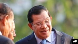 Cambodian Prime Minister Hun Sen, right, talks with top leaders of his party before an event by the ruling Cambodian People's Party marking the 36th anniversary of the 1979 downfall of the Khmer Rouge regime at their party headquarters in Phnom Penh, Cambodia, Wednesday, Jan. 7, 2015.