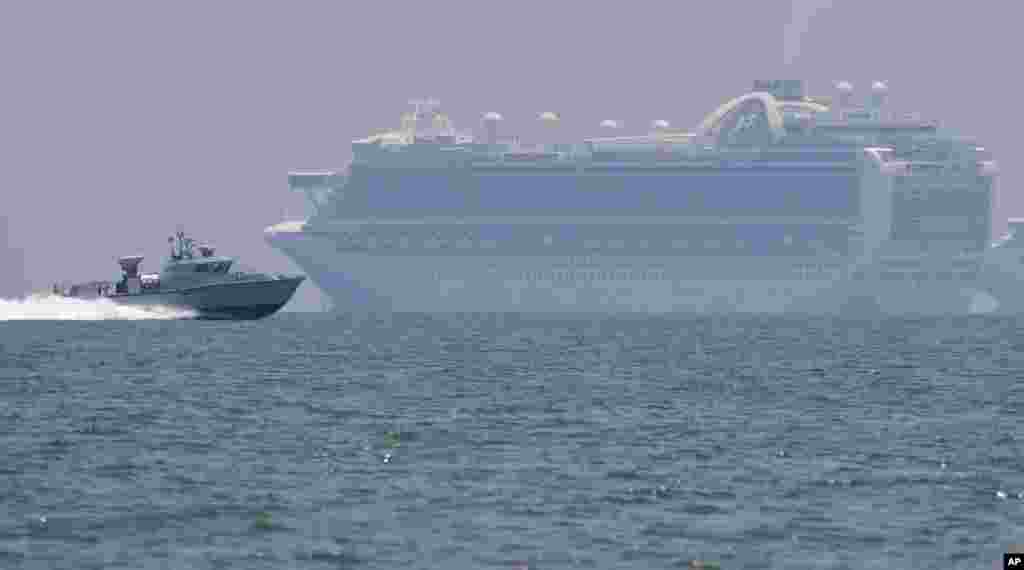 A Philippine military boat passes by the cruise ship Ruby Princess as it is anchored in Manila Bay, Philippines. The Ruby Princess which is being investigated in Australia for sparking coronavirus infections, has sailed into Philippine waters to bring Filipino crewmen home.