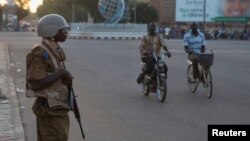 A soldier stands guard outside a building where a meeting between the military and opposition was taking place in Ouagadougou, capital of Burkina Faso, Nov. 2, 2014. 