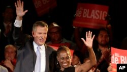 New York City Democratic Mayoral candidate Bill De Blasio, left, and his wife Chirlane wave to supporters at De Blasio election headquarters after polls closed in the city's primary election, Sept. 11, 2013, in New York. 