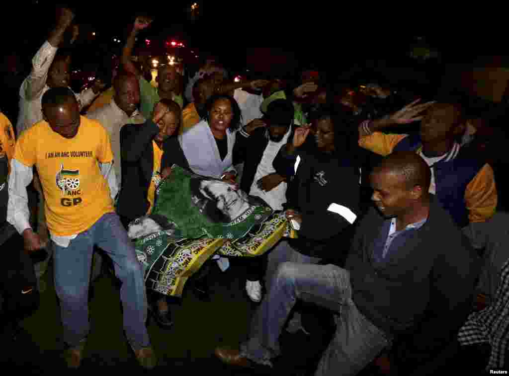 People chant slogans outside the house of former South African President Nelson Mandela after news of his death in Houghton, Dec. 5, 2013. 