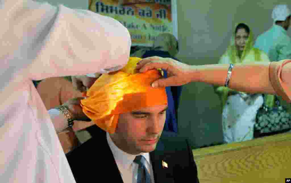 Wisconsin Governor Scott Walker is fitted with a head covering as he prepares to worship at the Sikh Religious Society, August 6, 2012.
