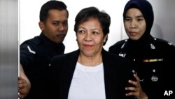 Australian Maria Elvira Pinto Exposto, center, is escorted by a police officer during a court hearing at Shah Alam High Court in Shah Alam, Malaysia, Dec. 27, 2017. 