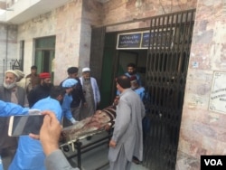 Injured man exits attack area on a stretcher after suicide bombers attacked a court in Charsadda, Pakistan, Feb. 21, 2017. (Photo: A. Momand / VOA Deewa Service)