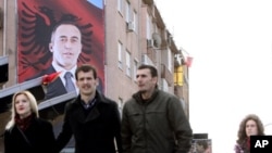Građani Kosova prolaze pored velikog postera sa likom bivšeg komandanta OVK-a i bivšeg premijera Kosova Ramuš Haradinaj