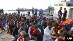 Les migrants africains sauvés par les garde-côtes libyens débarquent à la base navale de la capitale Tripoli le 12 juillet 2018.
