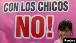 Une enfant se tient à côté d'une affiche avec l'inscription: "Touche pas aux enfants!" lors d'une manifestation contre les abus et la violence envers les enfants à Lima, au Pérou, le 8 février 2018.