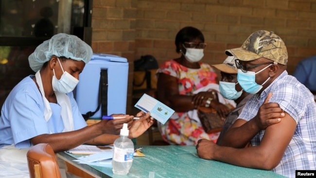 FILE - A man receives a certificate after being vaccinated against the coronavirus disease (COVID-19) at Wilkins Hospital in Harare, Zimbabwe, March 24, 2021.